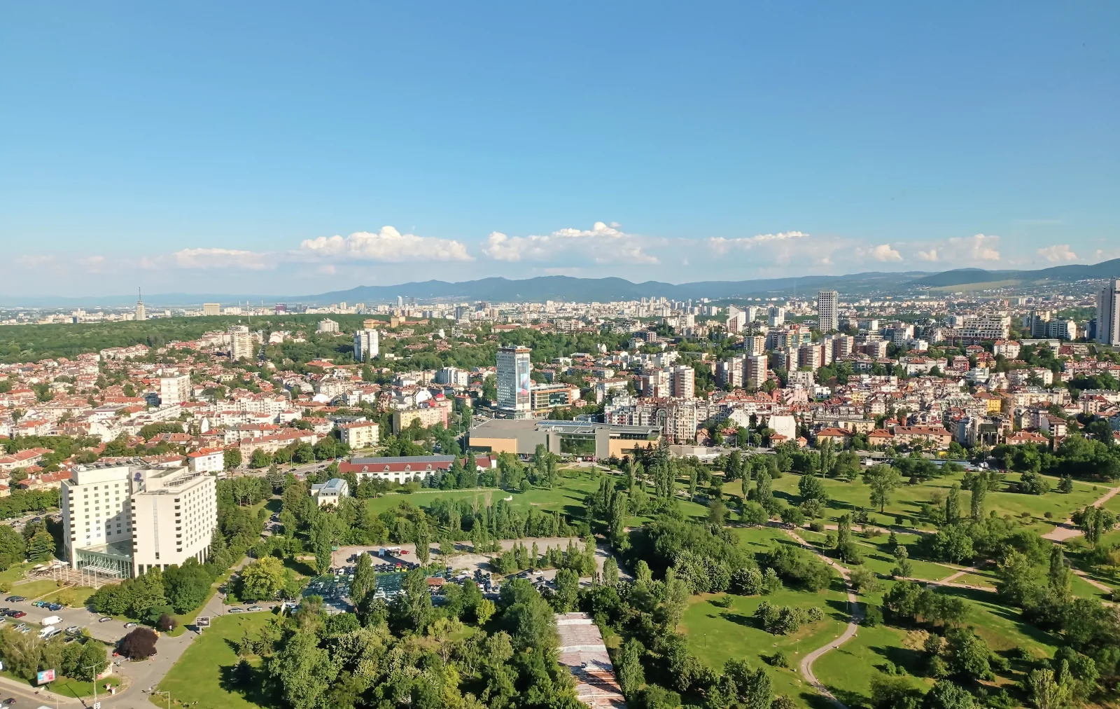 Panoramic view across Sofia rooftops towards the green hills.