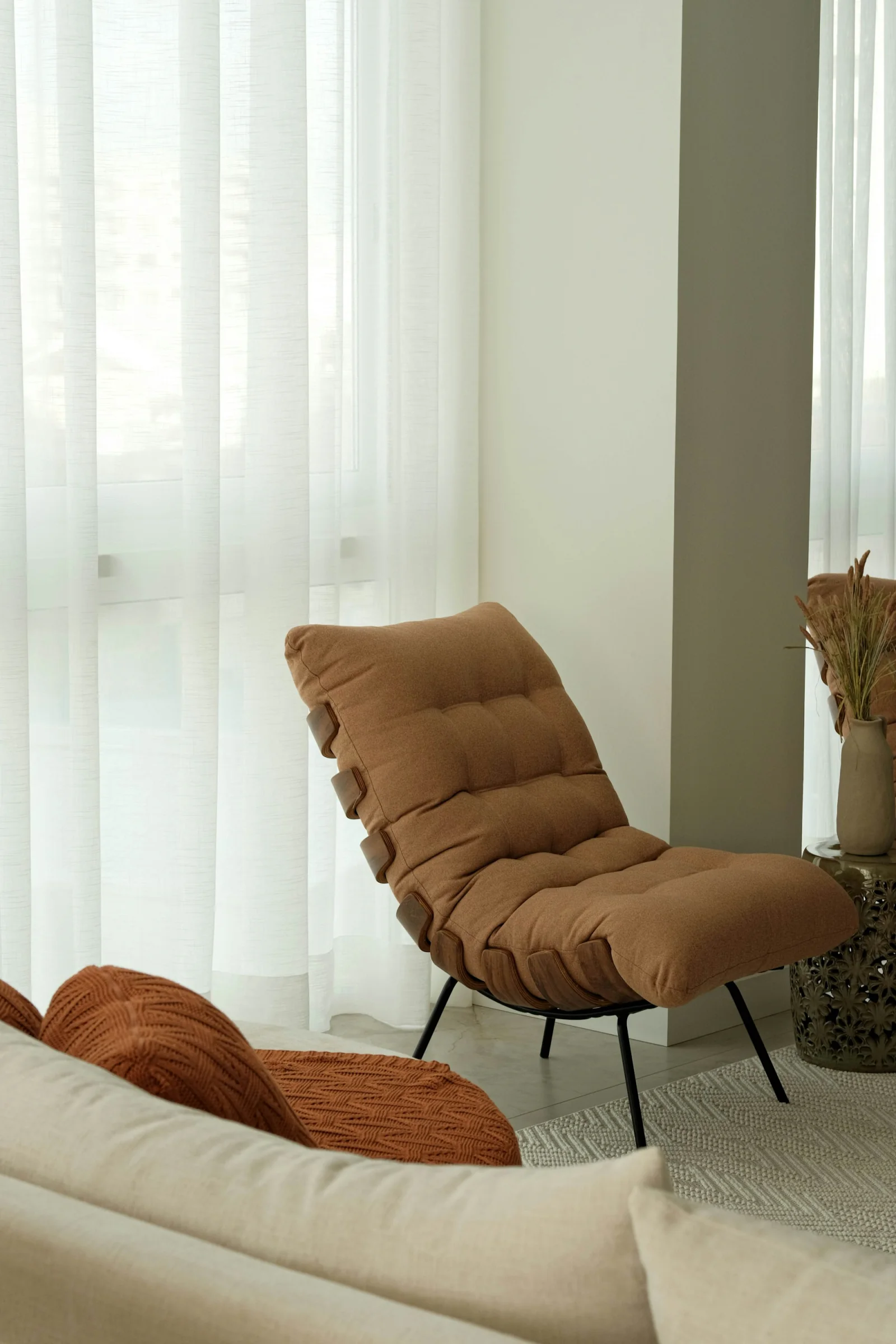 A reading chair beside sheer curtains in soft daylight.